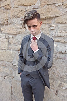 Stylish young man with a suit arranges his tie