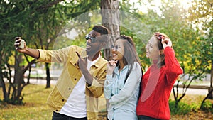 Stylish young people man and women are taking selfie wearing sunglasses posing and smiling holding smartphone during
