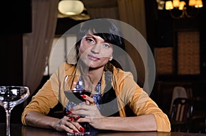 Stylish young woman drinking a glass of red wine