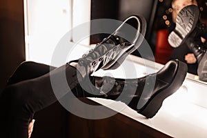 Stylish young woman in fashionable black beautiful leather shoes in trendy jeans near a vintage mirror with bright light bulbs in