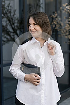 Stylish young woman in formal business clothing. Formal shirt and black clutch. Casual style