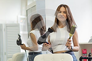 Stylish young woman hairdresser, female stylist with dental braces, modern barber girl holding professional comb, hair dryer