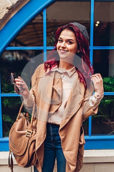 Stylish young woman having fun outdoors. Fashionable autumn outfit. Happy beautiful model showing tongue