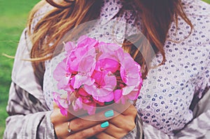 Stylish young woman holding bouquet of pink flowers