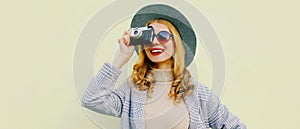 Stylish young woman photographer with vintage film camera wearing a round hat