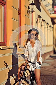 Stylish young woman on a retro bicycle. Outdoor fashion portrait