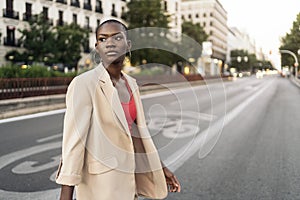 Stylish young woman with short hair looking away while crossing the street in the city