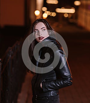 Stylish young woman standing in the night city.