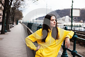 Stylish young woman in yellow hoody posing in the city streets.