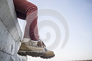 Stylishly dressed girl sits dangling and crossing her legs on a