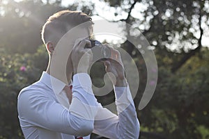 Stylishly dressed young man posing in a park. Retro style photo shoot.