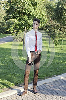 Stylishly dressed young man posing in a park. Retro style photo shoot.