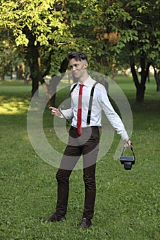 Stylishly dressed young man posing in a park. Retro style photo shoot.