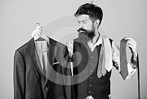 Stylist advice. Matching necktie with outfit. Man bearded hipster hold neckties and formal suit. Guy choosing necktie