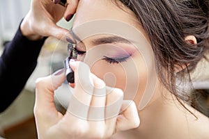 Stylist applying mascara on eyelashes of the model.