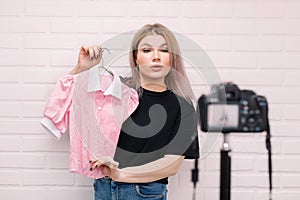 .A stylist blogger holds a blouse in front of the camera