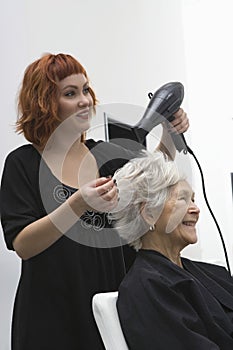 Stylist Blow Drying Senior Woman's Hair photo