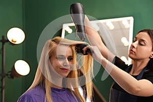 Stylist blow drying woman`s hair
