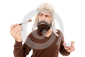 Stylist career. Freak visagiste. Applying makeup face tone. Powder cosmetics. Man bearded stylist wear hat hold brush