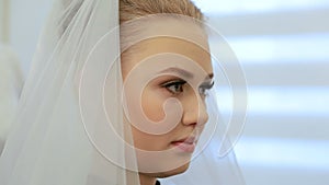 Stylist chooses the veil for future bride. Putting the bride`s white veil on the hair of the bride.