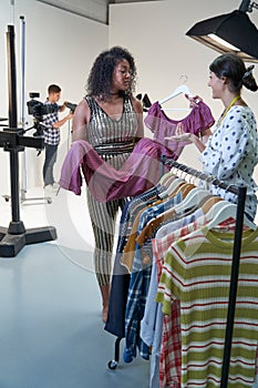 Stylist Choosing Clothes For Fashion To Wear On Photo Shoot In Studio
