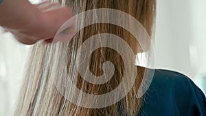 Stylist combs by brush the female hair after haircut in beauty hairdresser salon