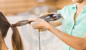 Stylist curling hair for young woman. Girl care about her hairstyle