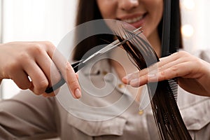 Stylist cutting hair of client in professional salon, closeup