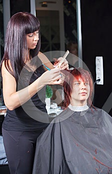 Stylist cutting woman hair in salon