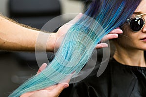 Stylist demonstrates his work with Beautiful girl. Barber haircut dyed hair color blue