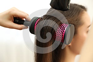 Stylist drying client`s hair in beauty salon, closeup