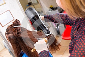 Stylist Drying Hair of Brunette Client in Salon