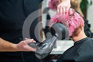 Stylist is drying woman hair.