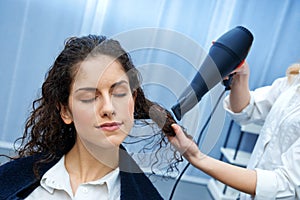 Stylist drying woman hair in salon