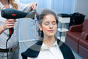 Stylist drying woman hair in salon