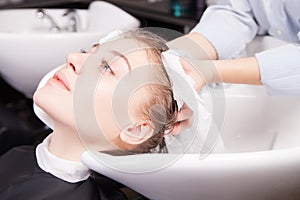Stylist drying woman hair with towel in salon