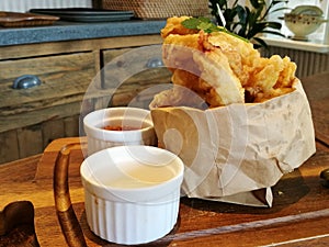 Stylist food, deep fried calamari on paper bag with chilli sauce and mayonnaise or tartar sauce serve on the wooden tray with blur