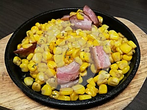 Stylist food, fried sweet corn bacon and chop parsley with butter and seasonings serve on the hot pan plate focus-on-foreground wi