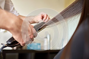 Stylist with iron straightening hair at salon