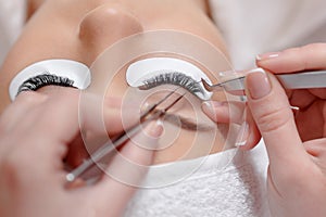 Stylist lengthening lashes for female in a beauty salon.