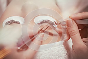 Stylist lengthening lashes for female in a beauty salon.