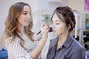 Stylist makeup artist doing makeup and hair in a beauty salon. Professional make-up