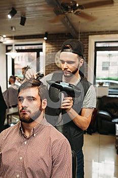 Stylist making modern hairdo for young man