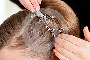 Stylist pinning up a bride's hairstyle photo