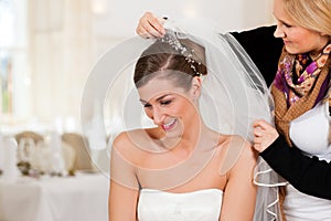 Stylist pinning up a bride's hairstyle photo