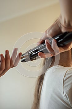 Stylist& x27;s hands straightene hair on a curling iron