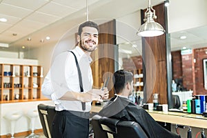 Stylist Smiling While Grooming Client`s Hair In Barber Shop