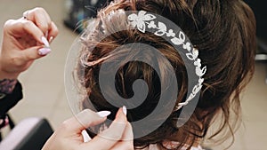 Stylist straightens her hair girl. Close - up of the stylist`s hands. Girl sitting on makeup