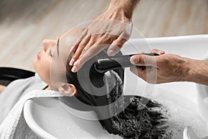 Stylist washing client`s hair at sink