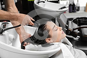 Stylist washing client`s hair at sink